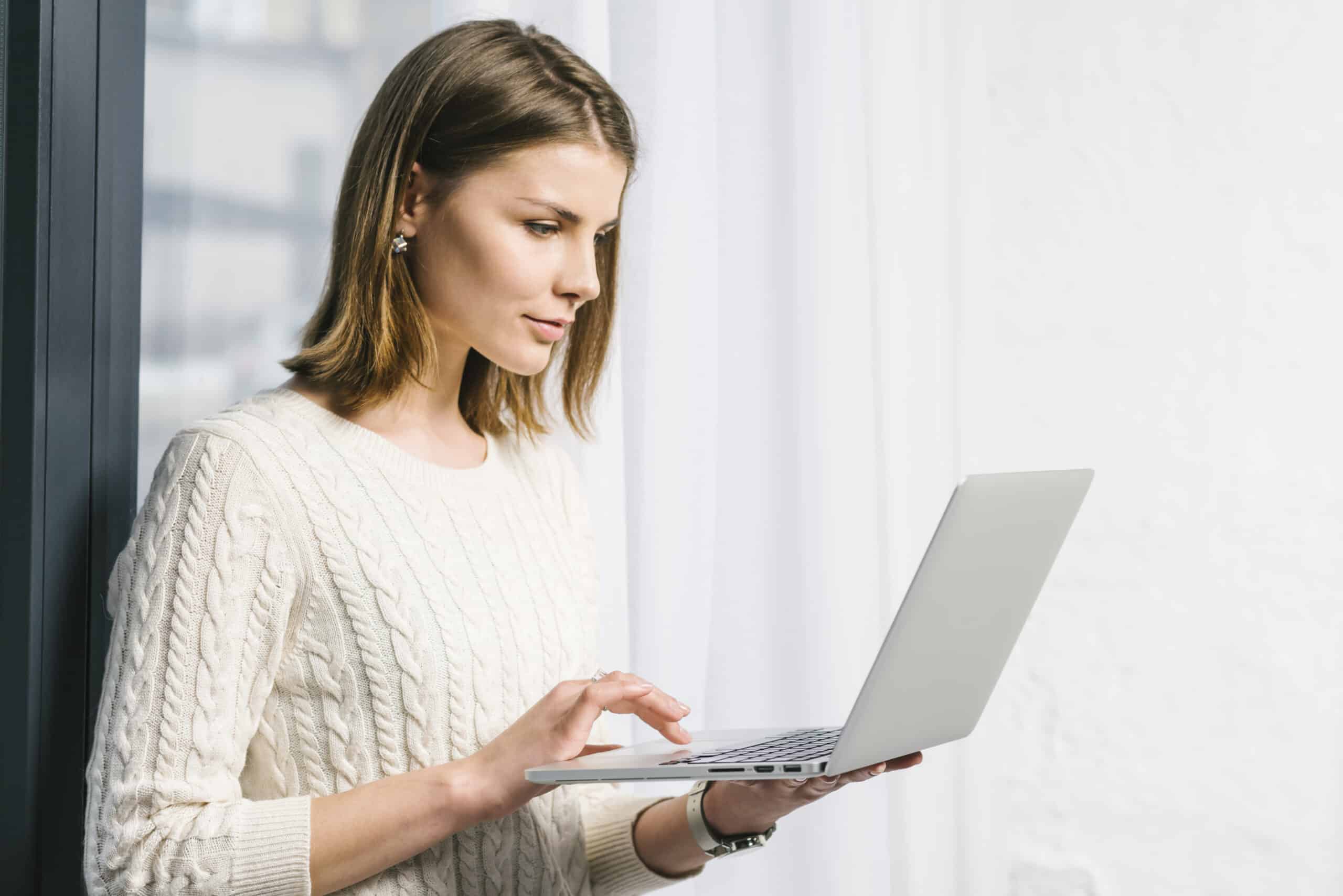 lovely-woman-using-laptop-near-window