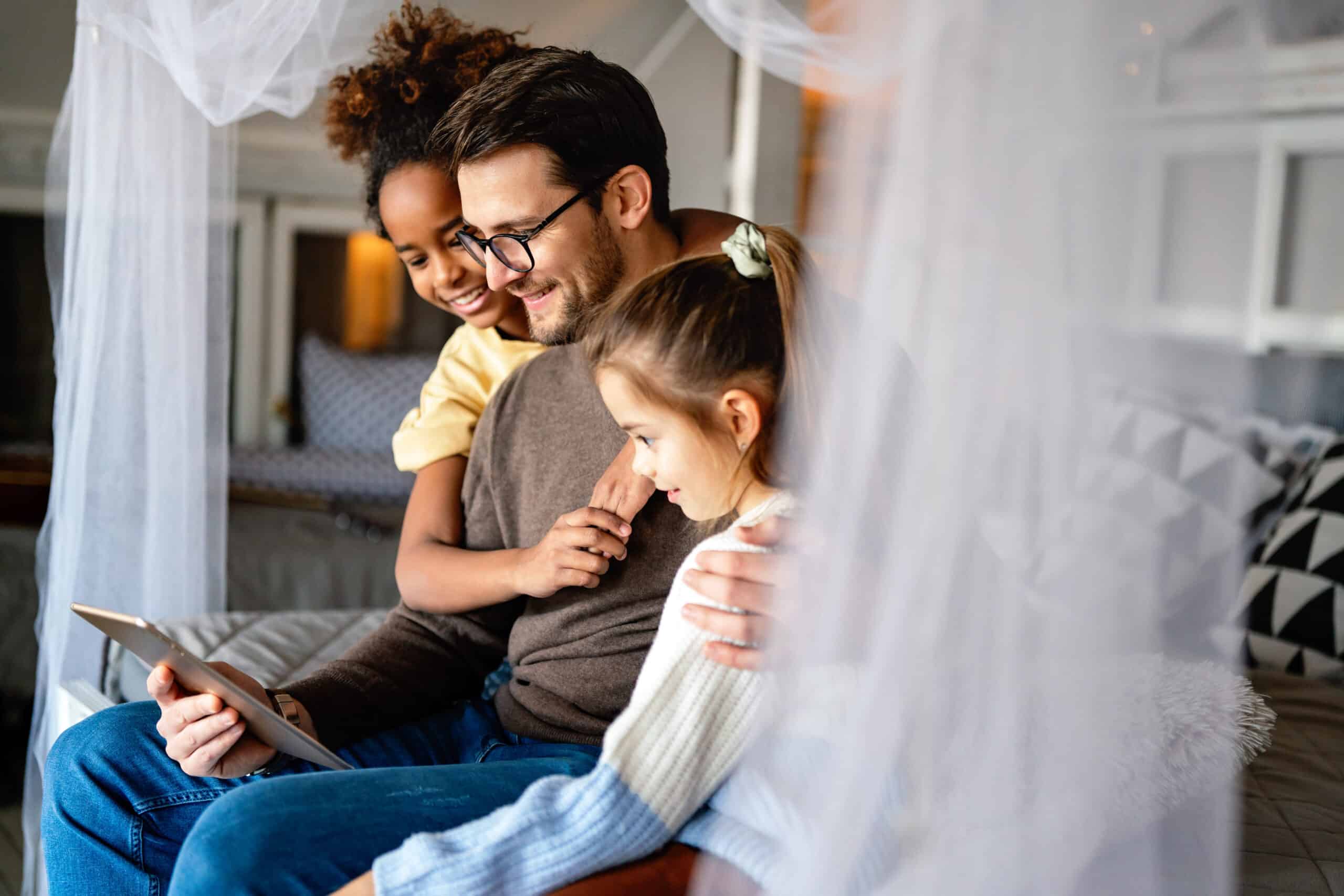 Multiethnic happy children and father studying at home for online school